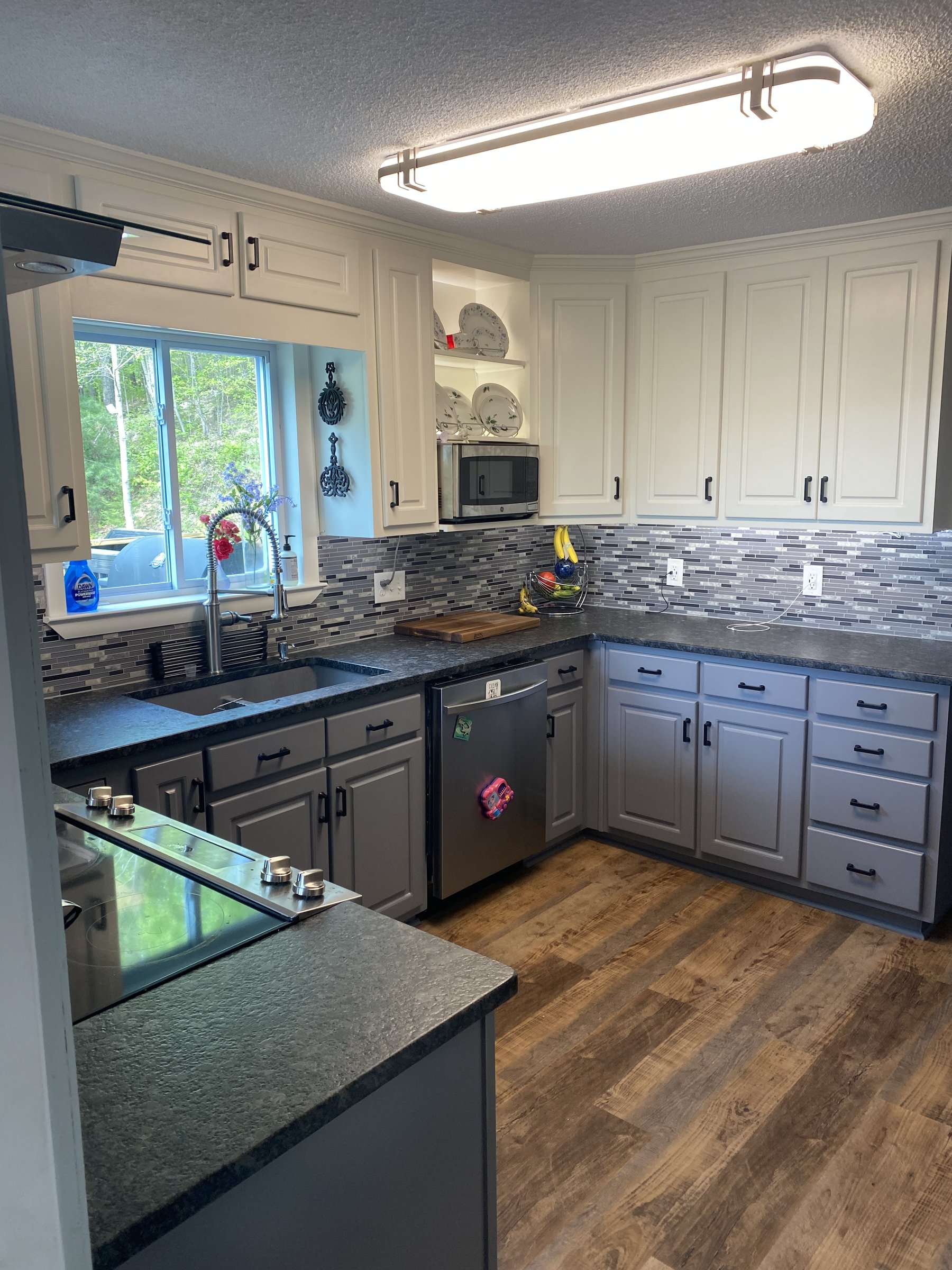 Finished kitchen remodel with white and gray cabinetry, tile backsplash, and hardwood floors by Top Rock Solutions in Chattanooga